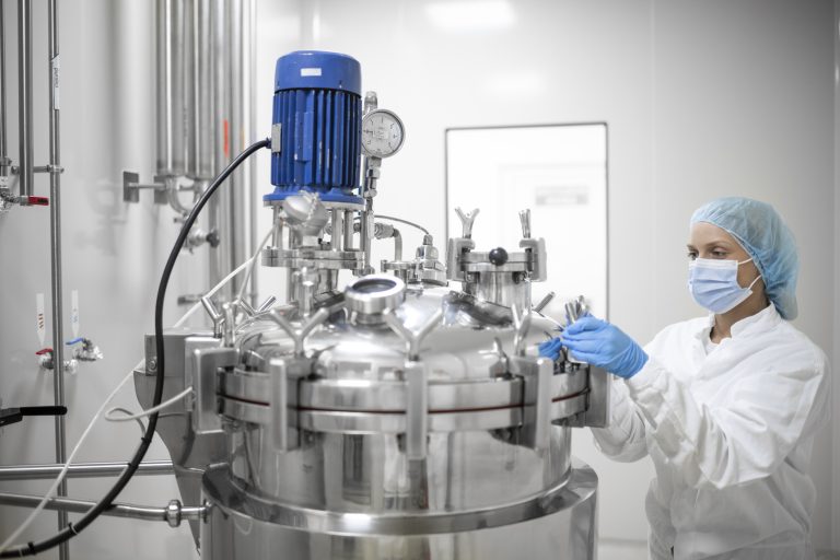 A female worker in protective gear operates high-tech equipment in a laboratory