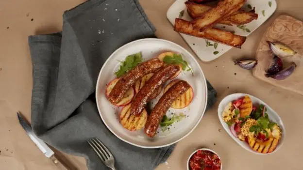 A picture of several plates of food, including meat-free sausages, parsnips and shallots.